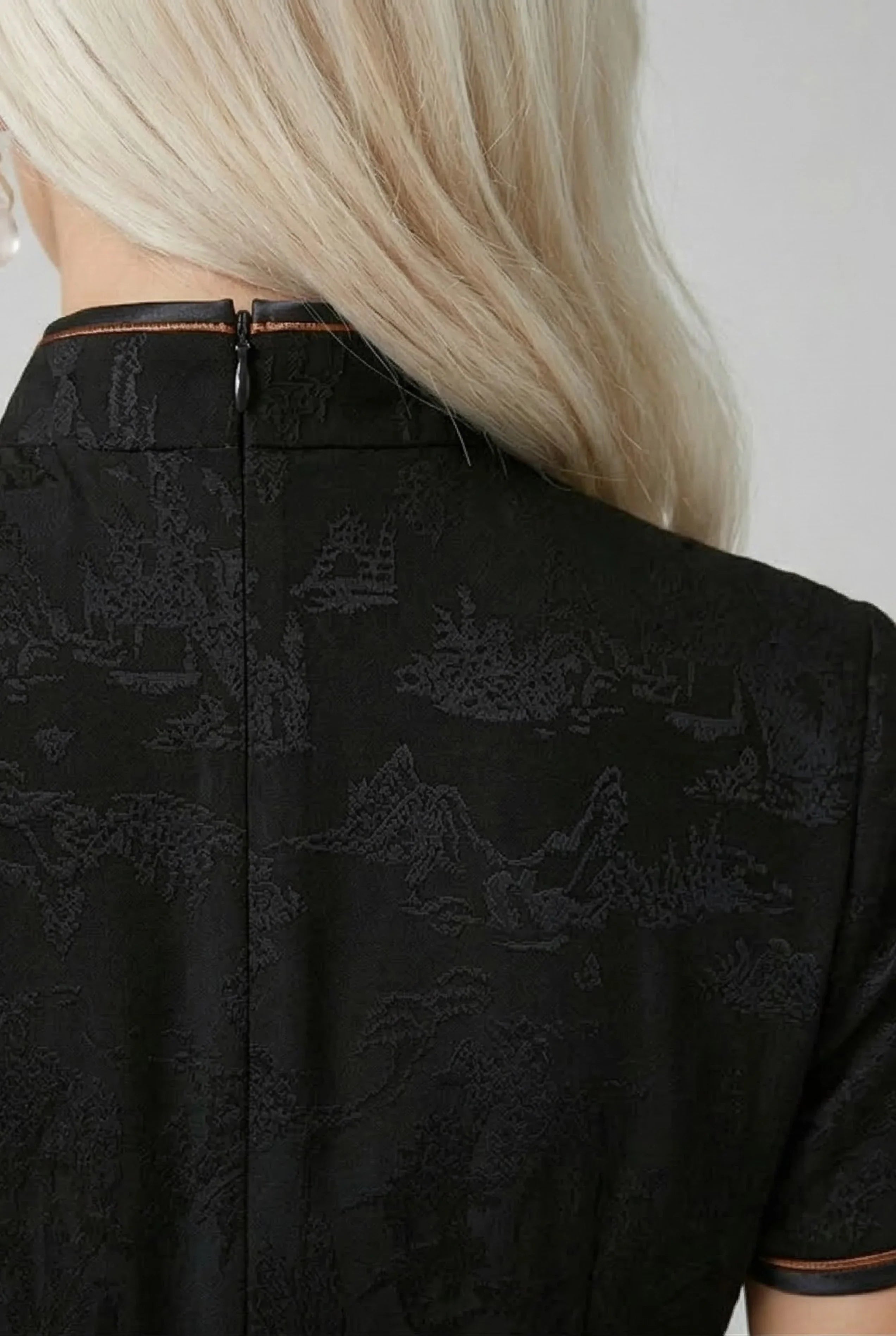 Detailed shot of the high-quality black silk fabric texture and shoulder stitching of a traditional Chinese dress.