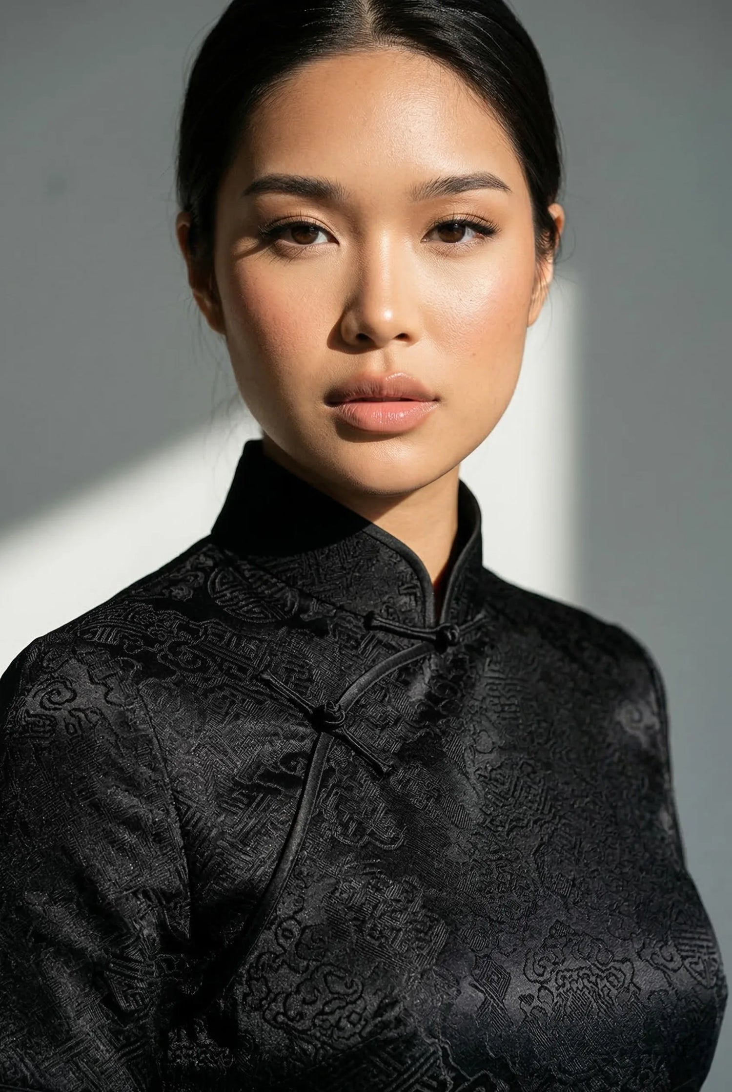 Professional black silk qipao with an intricate damask pattern by Maison Hua, highlighting a sharp straight-line silhouette and a high Mandarin collar