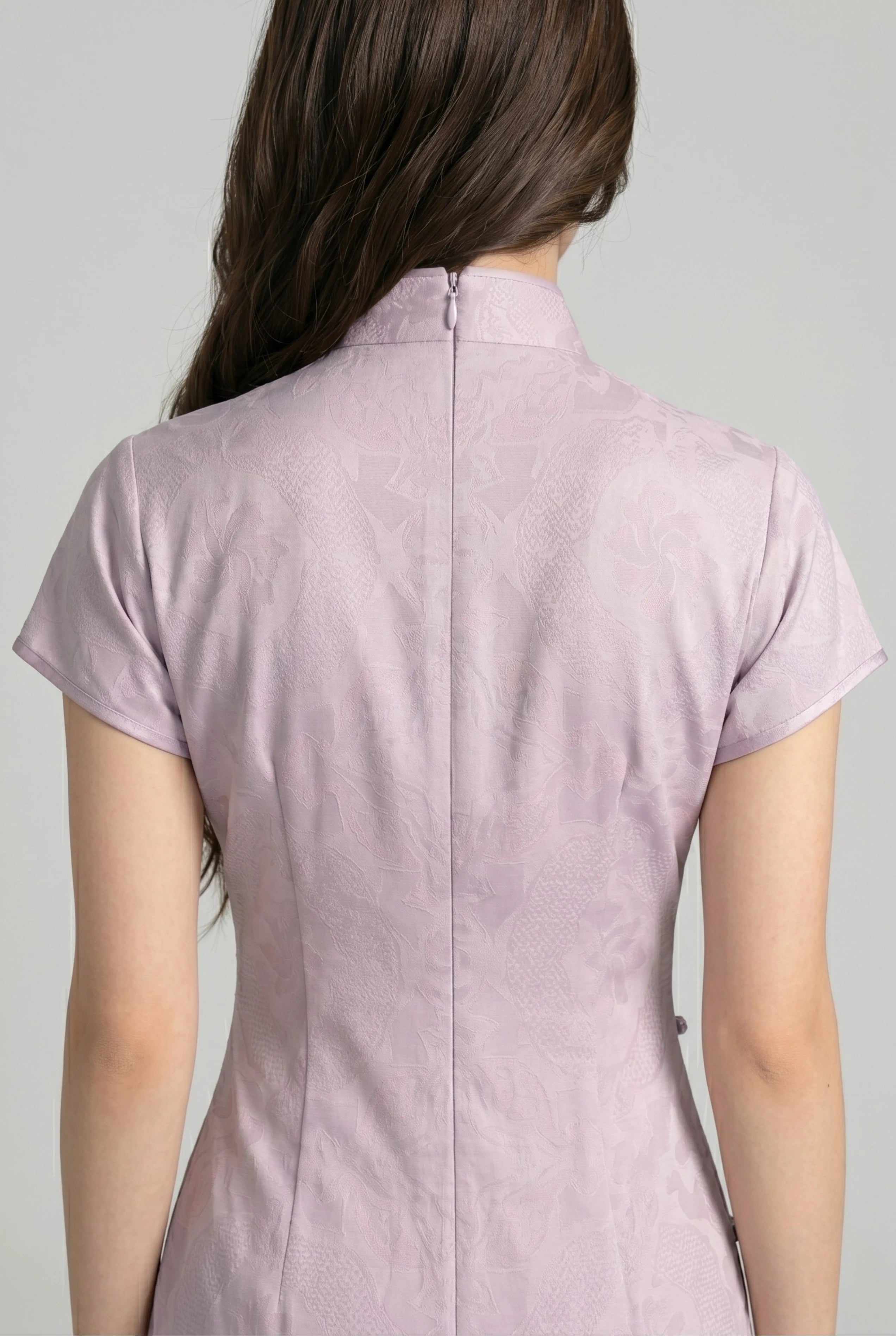 Close-up back view showing the hidden zipper closure, cap sleeve seams, and high collar structure of the purple cheongsam