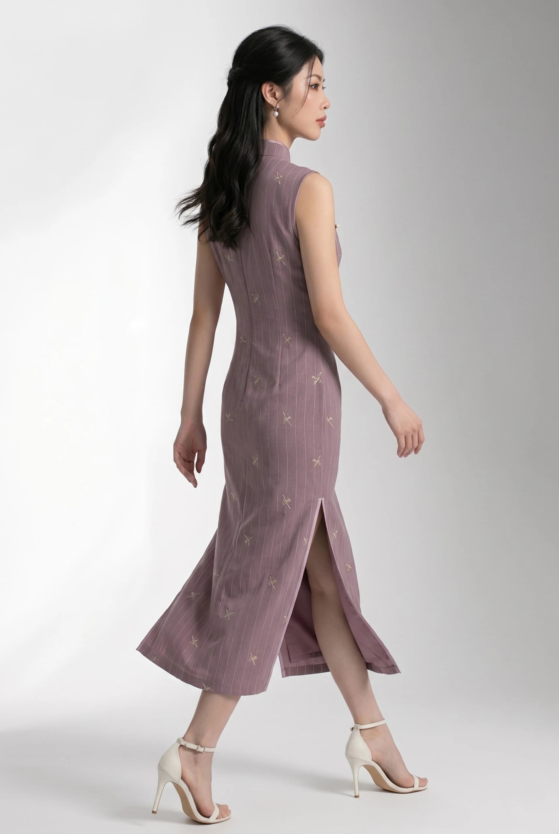 Side view of a woman walking in a purple Chinese style cheongsam dress, showcasing the high side slit.