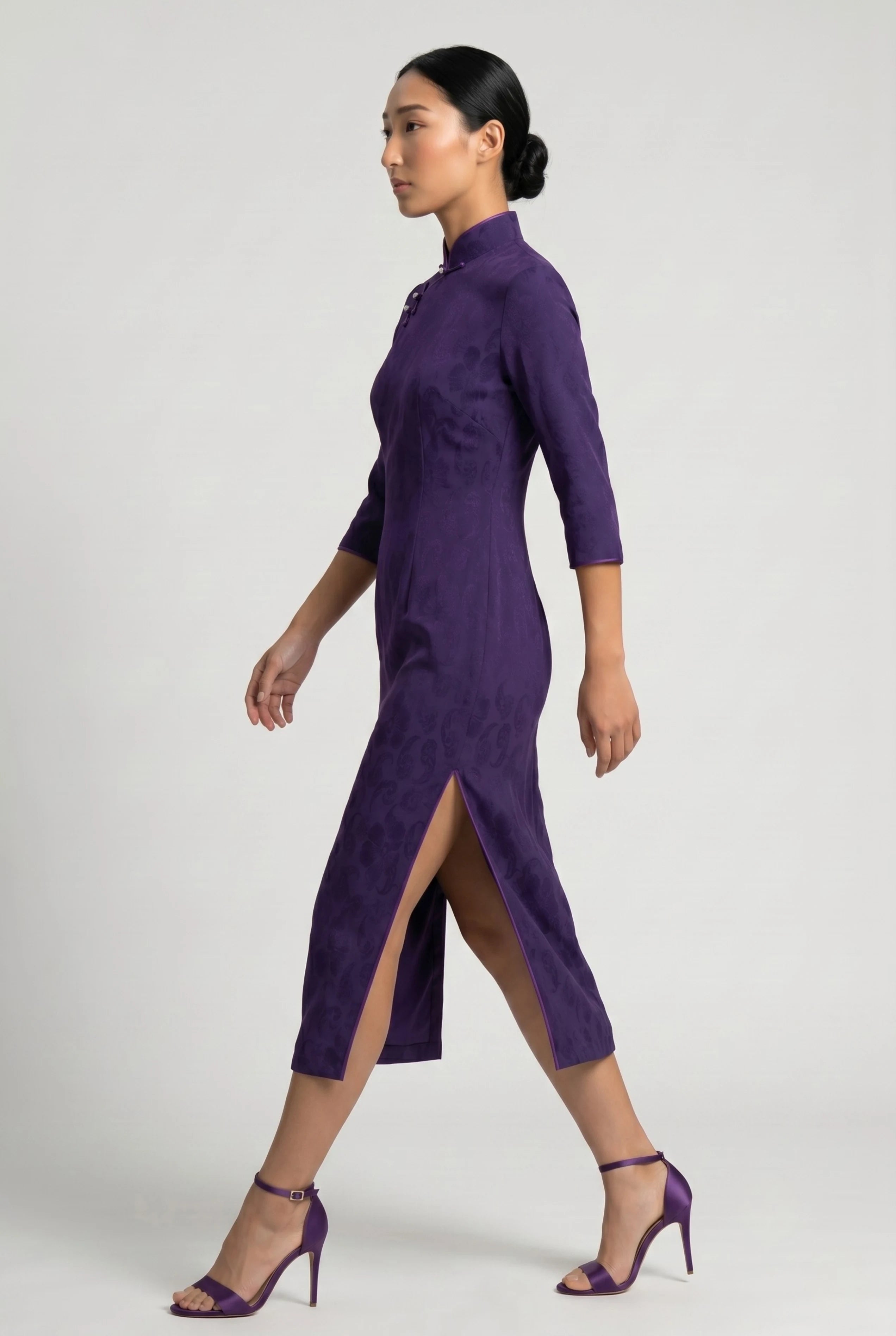 Full-body side profile view of a woman in stride wearing the purple velvet cheongsam dress paired with purple heels