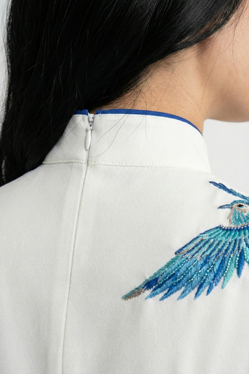 Detail of the high collar and back zipper on a white qipao dress