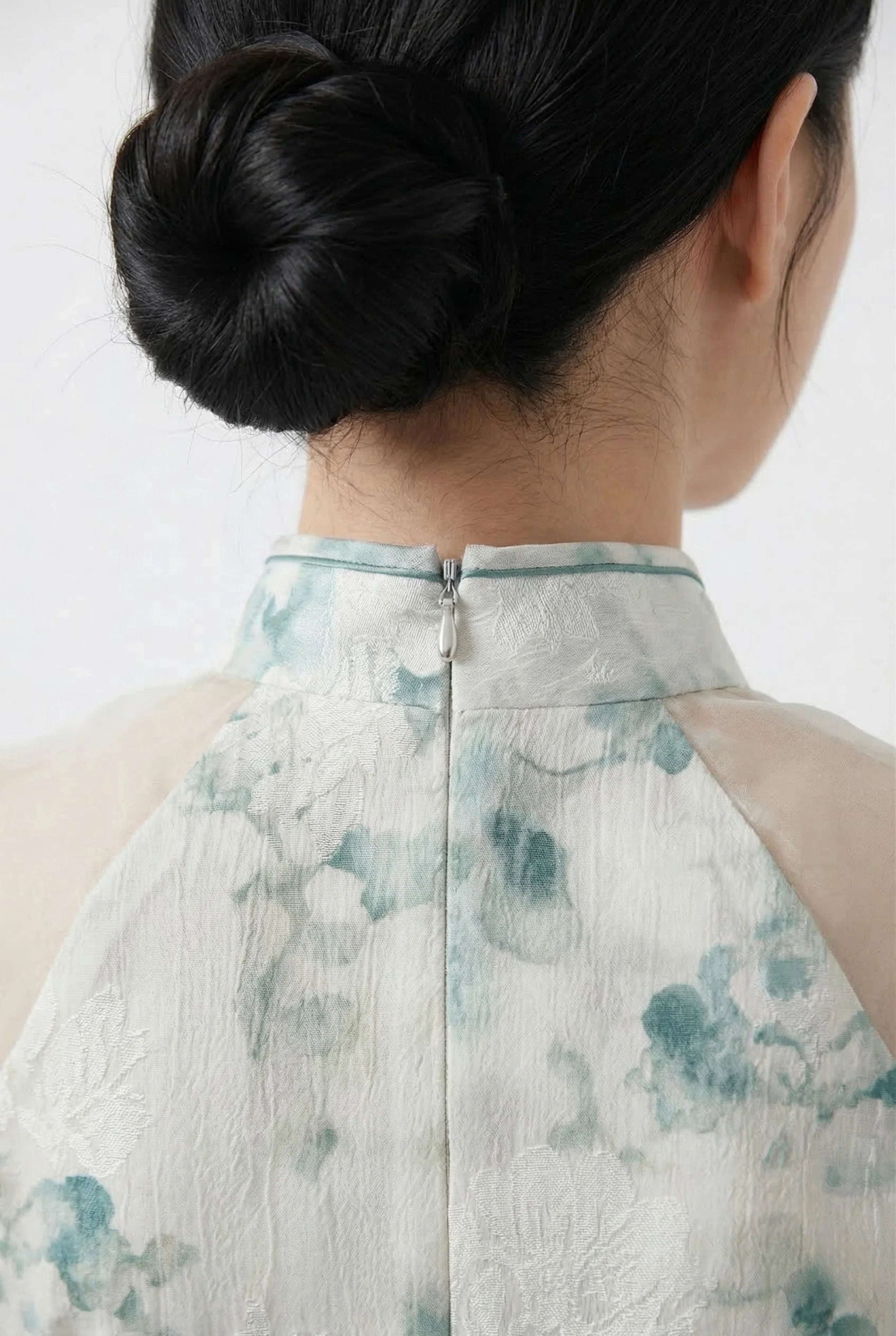 Close-up of the high mandarin collar and discreet back zipper on a floral print Maison Hua Qipao.