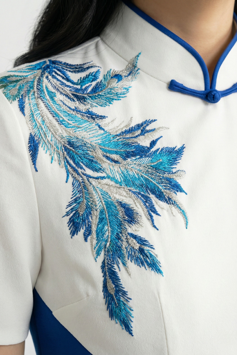 Close-up of blue and silver peacock embroidery on a white qipao bodice