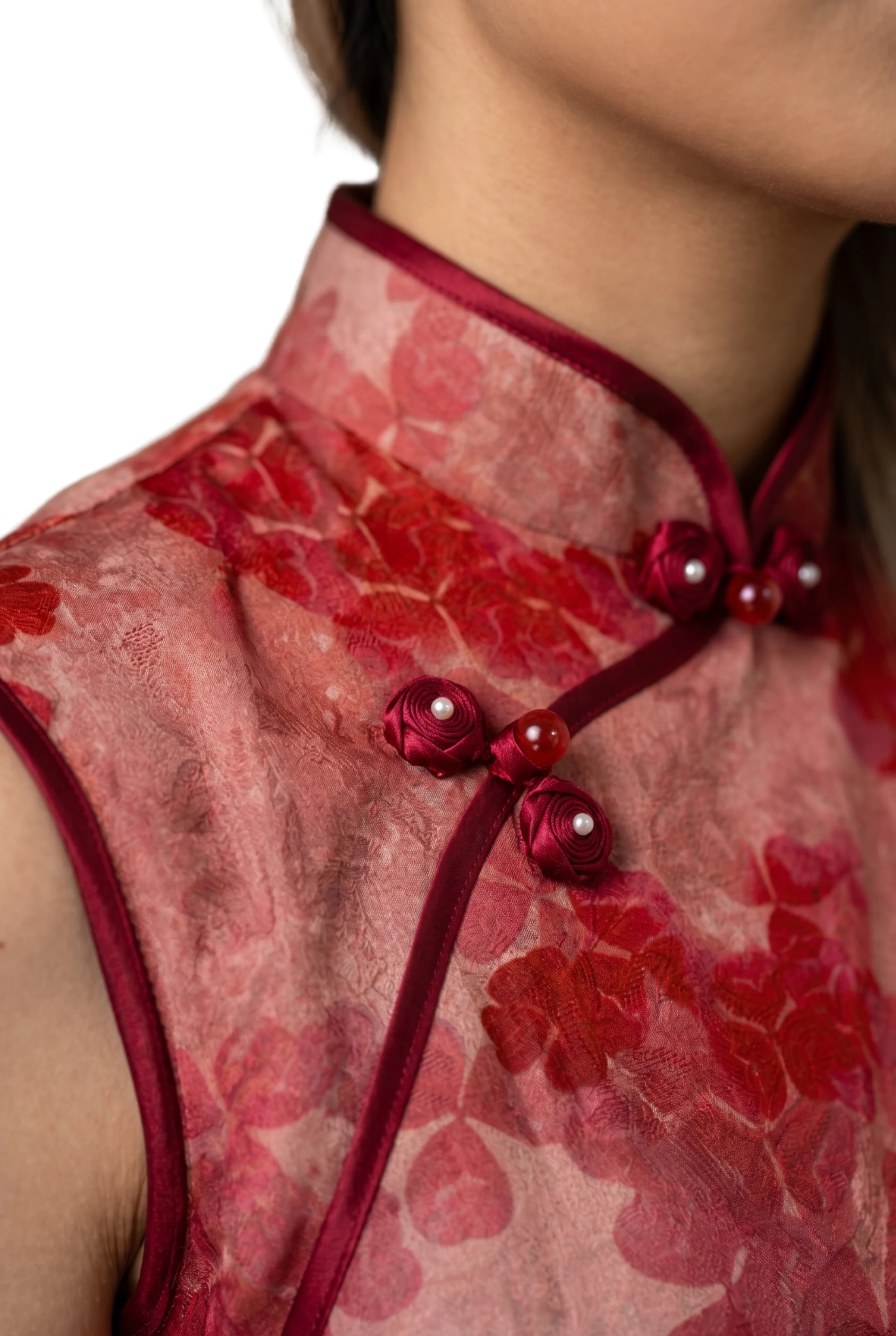 Close-up of the mandarin collar, traditional frog buttons with pearl details on the red dress.