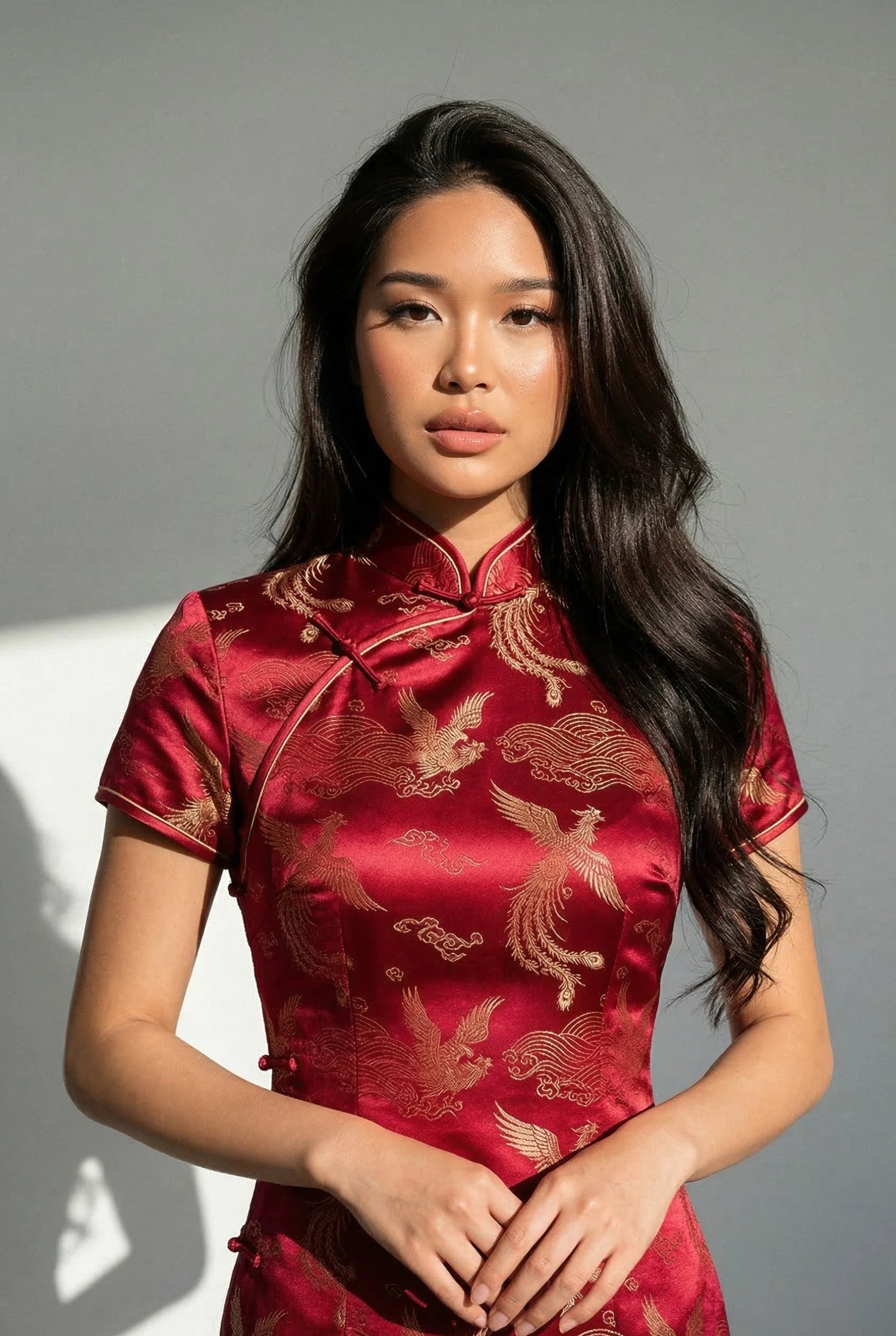 Red silk cheongsam dress by Maison Hua featuring traditional gold phoenix weaving patterns, a contemporary satin finish, and reinforced seams for structural durability