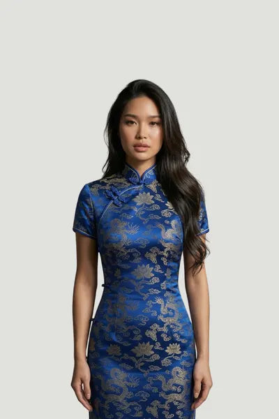 A model wearing a royal blue qipao by Maison Hua, featuring a rich gold floral and dragon brocade pattern, short sleeves, and a traditional high Mandarin collar