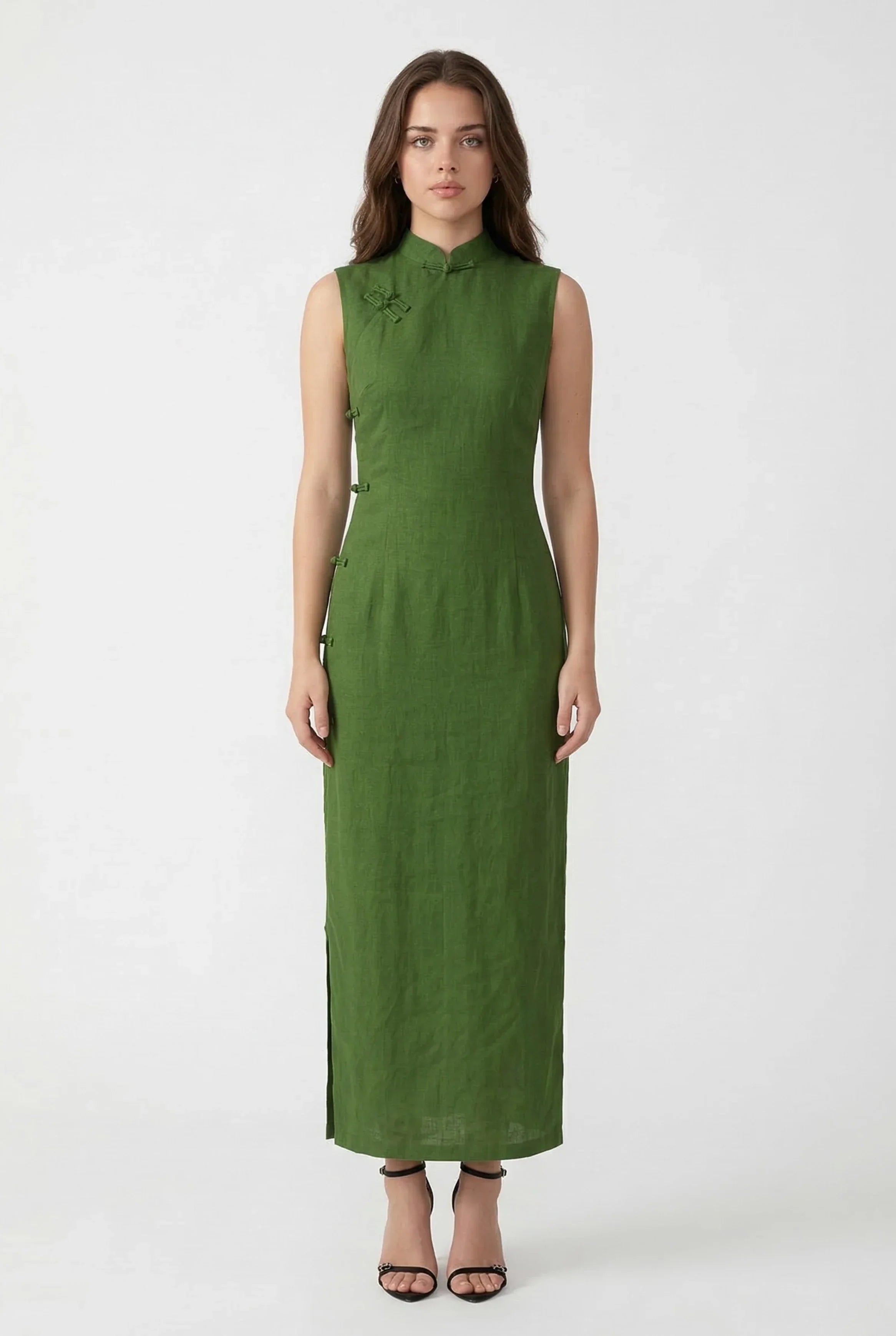 A woman wearing a simple and elegant sleeveless green linen qipao maxi dress with traditional frog button closures.