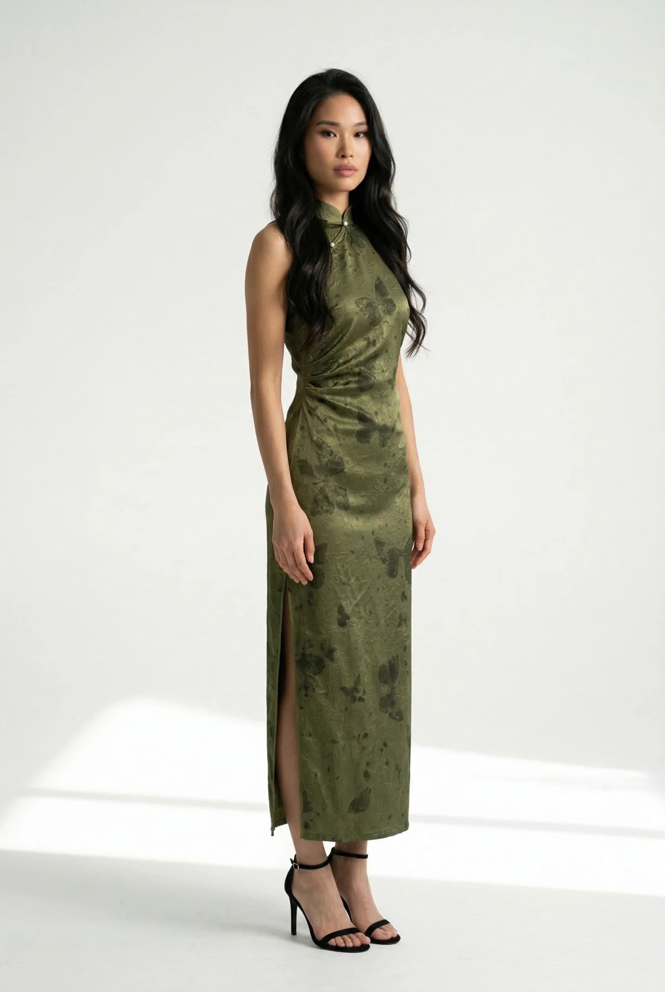 Side profile of a sleeveless olive green Chinese dress highlighting the butterfly print and high side slit.