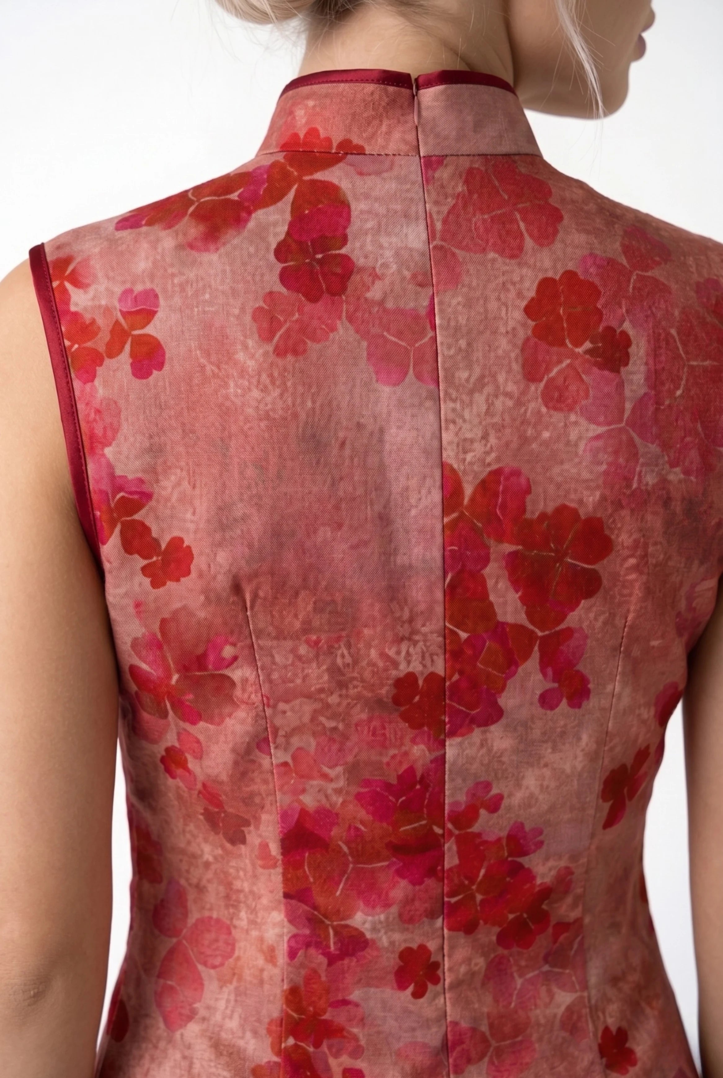Detail view of the high back collar and intricate floral pattern of the sleeveless red qipao.