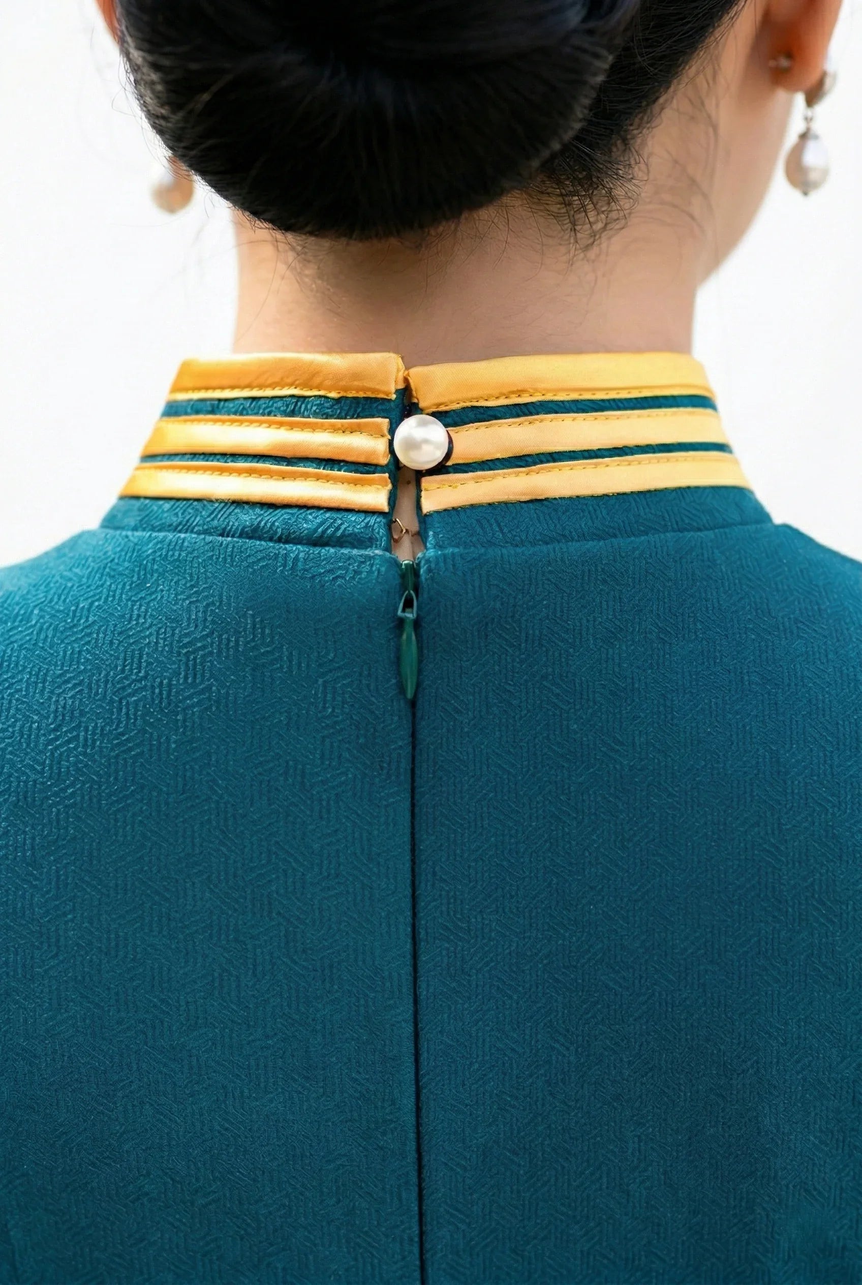 Back collar detail showing pearl button on a teal cheongsam
