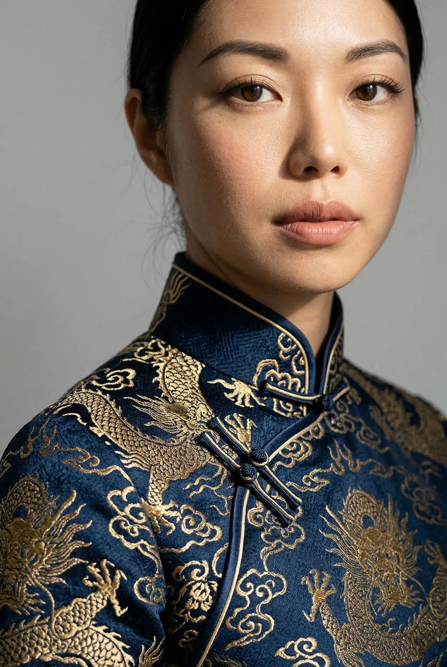 High-quality traditional Chinese cheongsam in navy blue with intricate gold dragon embroidery, showcasing professional fit and material grammage by Maison Hua