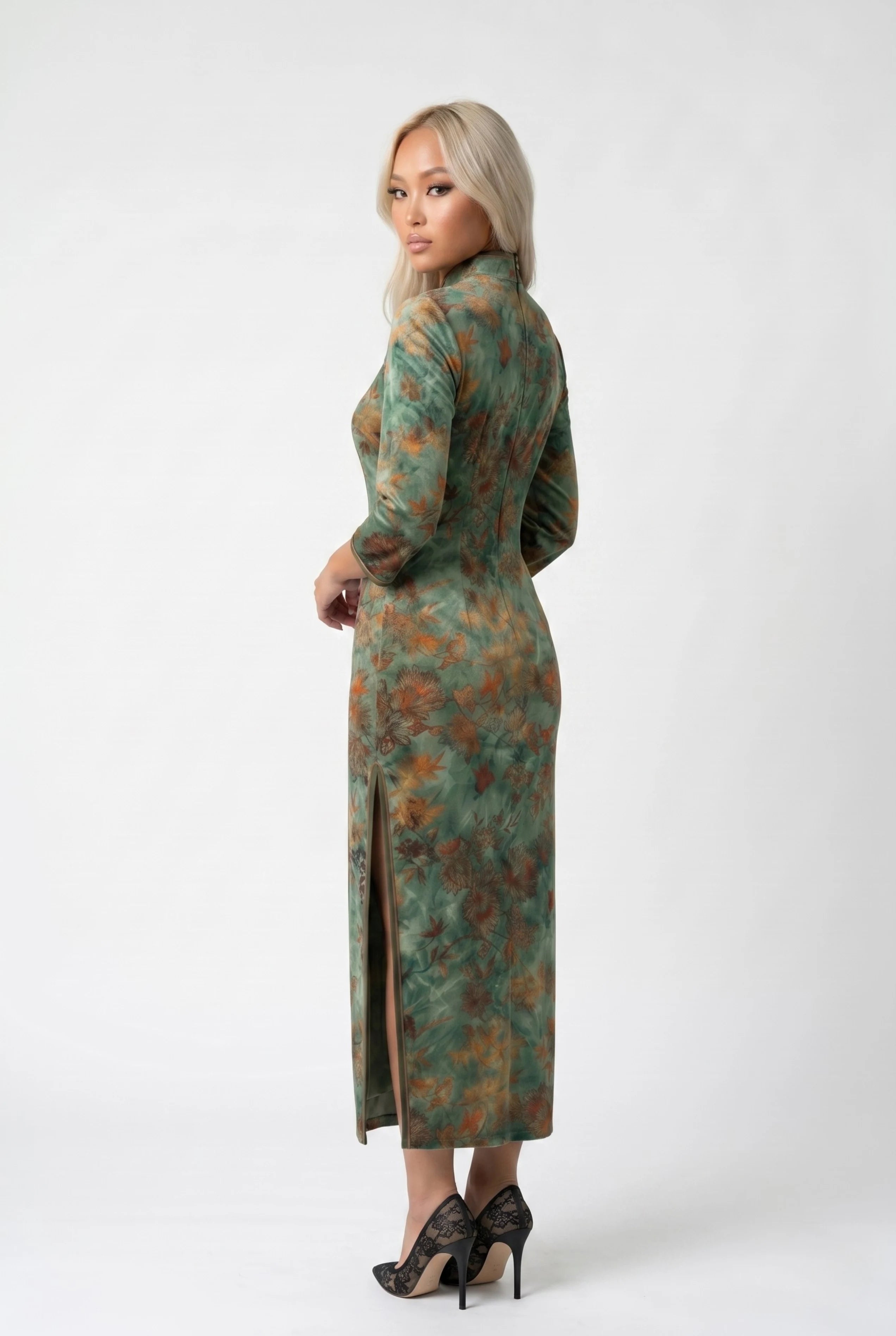 Three-quarter back profile view highlighting the form-fitting design and side slit of the green floral cheongsam