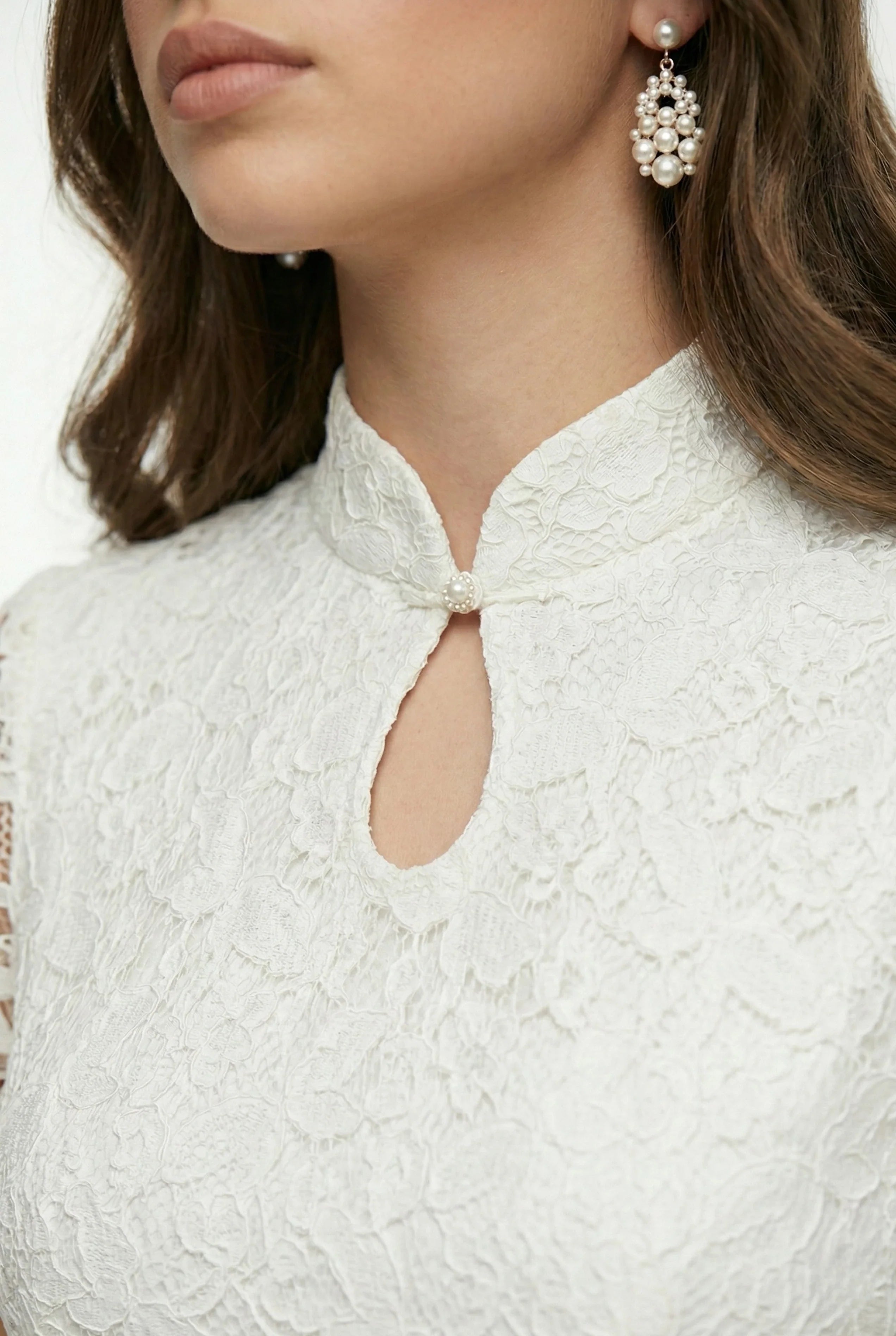 Detail of the keyhole neckline and mandarin collar on a white lace qipao