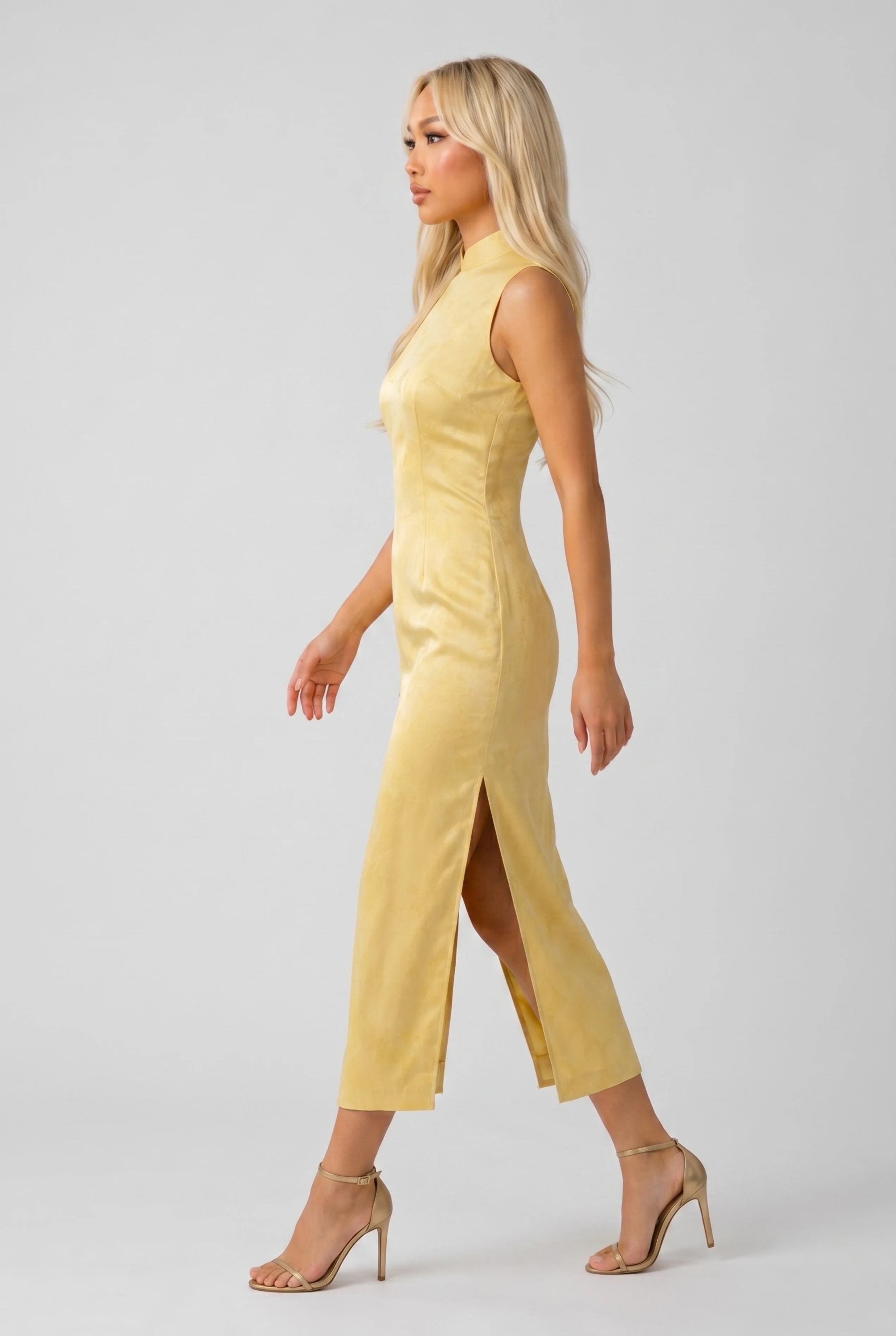 Full-body side profile view of a woman in stride wearing the yellow embroidered qipao
