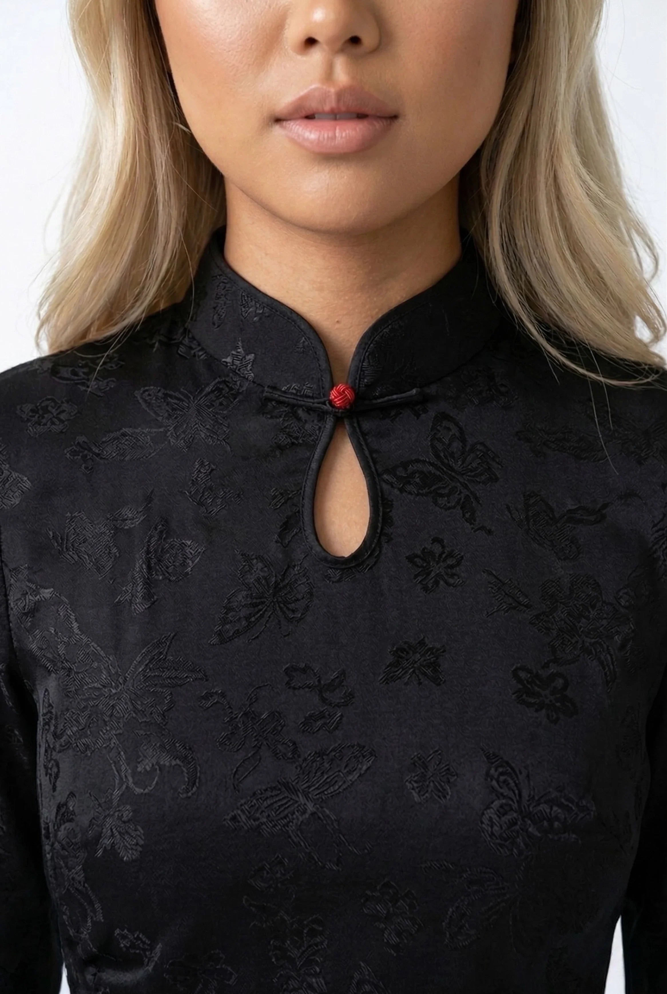 Close-up of the black cheongsam's mandarin collar with a red frog button.